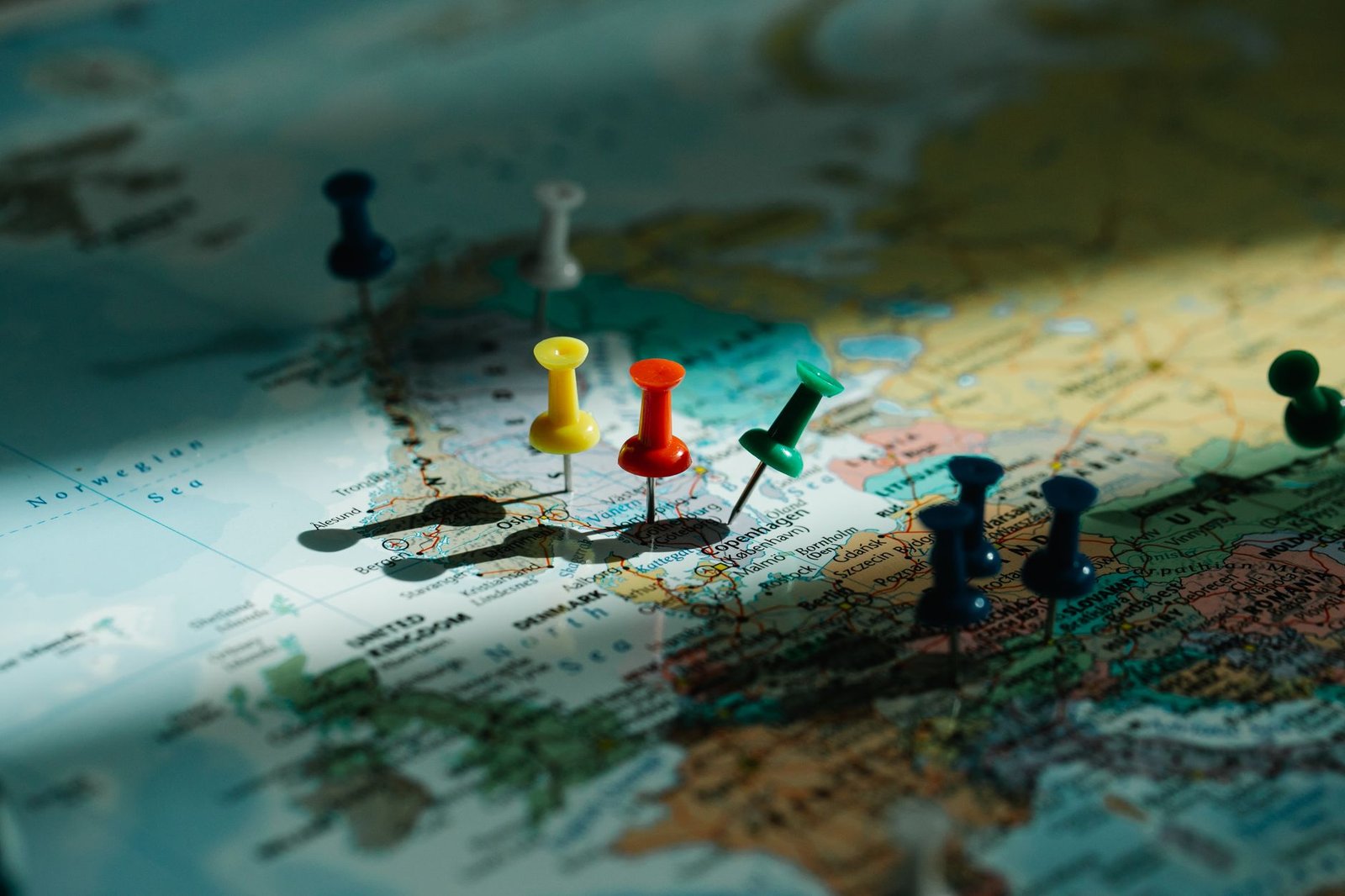 A close-up view of colorful push pins marking locations on a detailed world map.